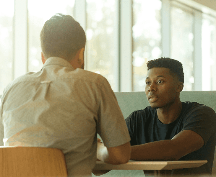 A young man sitting at a table, learning from his mentor. Integrea Community Mental Health System offers many services for those mental health illnesses and substance use disorders.