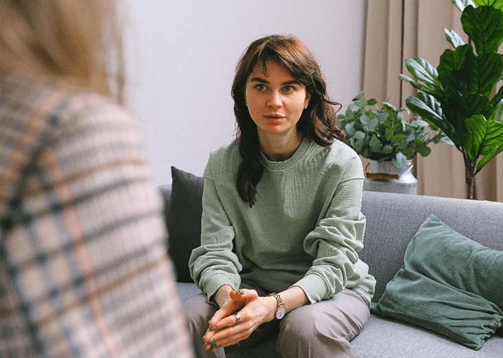 A young woman sitting on a couch speaking with a therapist. Integrea Community Mental Health System offers many services for those with mental illnesses.