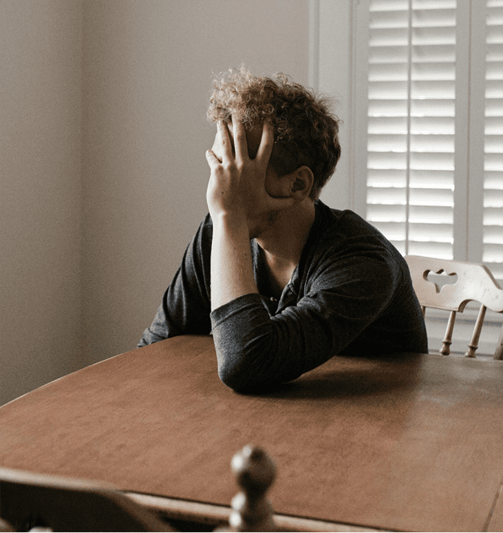 A man sitting at a table with his head in his head, frustrated. Integrea Community Mental Health System offers many services for those mental health illnesses and substance use disorders.