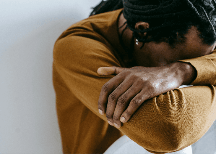 A man sitting against the wall with his head down. Integrea Community Mental Health System offers many services for those with mental illnesses.