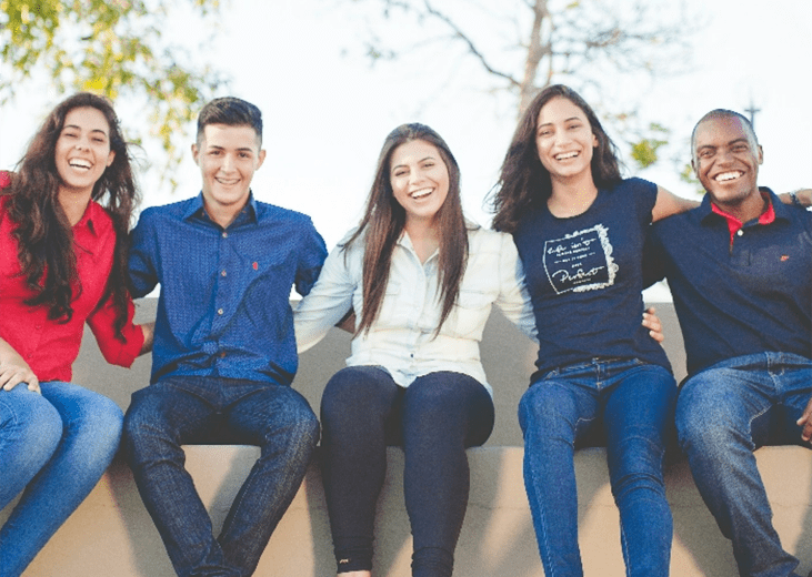 A happy group of smiling people sitting on a wall. Integrea Community Mental Health System offers many services for those mental health illnesses and substance use disorders.